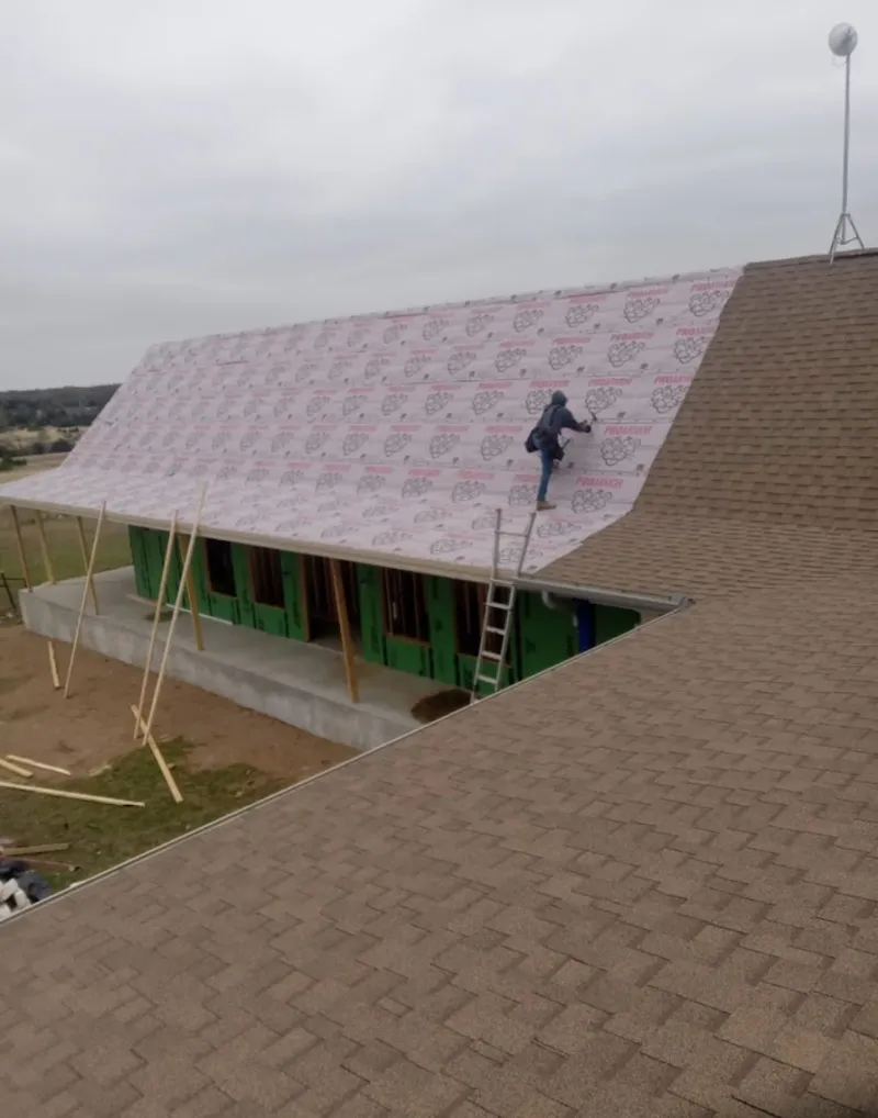 Worker preparing underlayment for a metal roof installation in Berryville